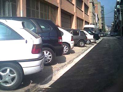 Cotxes aparcats sobre la vorera al carrer Dos de Maig.